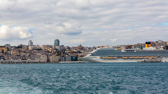 Istanbul skyline as seen from Bosphorus. Cruise liner Costa Venezia at port. Sunny day, beautiful clouds at background, sea at foreground. October 17, 2022 - Istanbul, Turkey