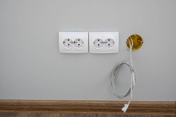 deux prises électriques blanches de la norme européenne. à côté d’eux du mur vient le fil d’alimentation, l’internet - electric plug outlet electricity cable photos et images de collection