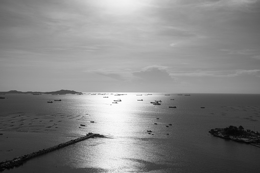 Black and white photo of sea and sky with sunlight or sunset high angle view at Sriracha District of Chonburi Province Can see Koh Loi, Sriracha Port and Ship It is famous tourist attractions
