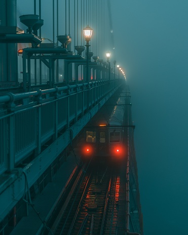 A stunning shot of a train moving along a bridge in a misty, moonlit evening, overlooking a tranquil beach