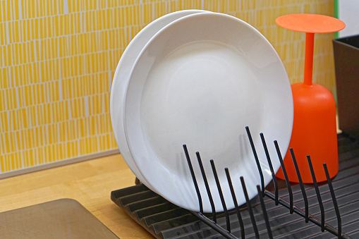 White ceramic plates and glass at drying rack kitchen counter