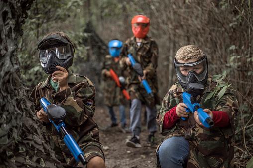 Young children playing paintball together during a skirmish