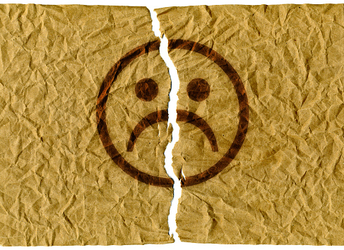 Background of crumpled paper with, torn sheet, sad emoticon