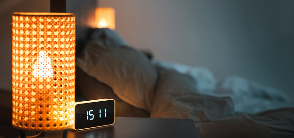 Smart home devices. Alarm clock on the bedside table. Interior of the bedroom. Night lights connected to the home automation system. Copy space. Horizontal banner.