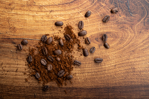 Coffee beans and ground coffee on wooden table