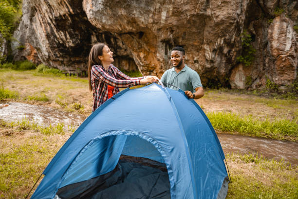istock Happy couple having fun placing tent by the stream 1501767229