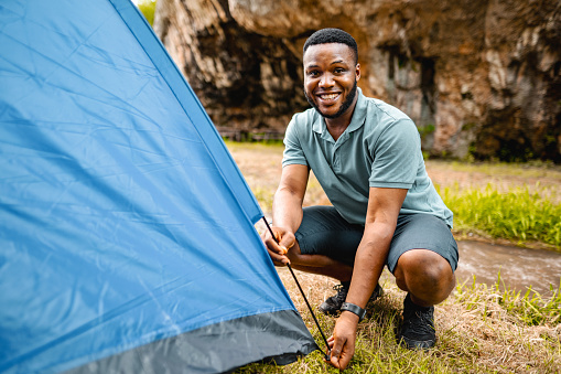 A young man setting up a tent by the big rock