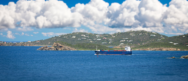 A freight ship steams through a tropical sea.