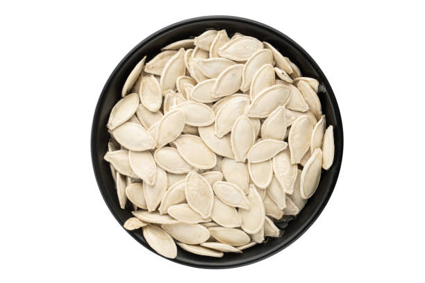 White pumpkin seeds in a plate, top view. Isolated on white background. White pumpkin seeds in a plate, top view. Isolated on white background. File contains clipping path rapeseed shell stock pictures, royalty-free photos & images