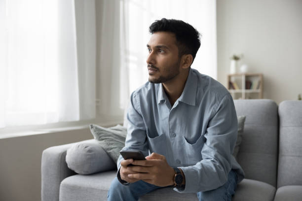 istock Serious thoughtful young adult Indian guy holding digital gadget 1501769961