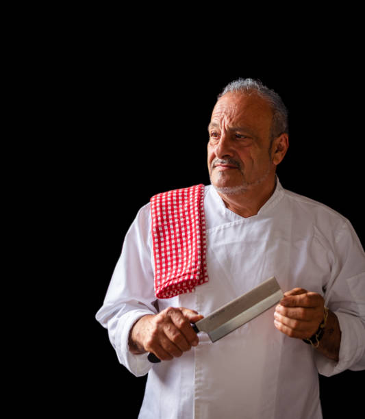 istock senior chef portrait, studio portrait, black background, vertical image,Epicurean Elegance: The Culinary Maestro in Monochrome 1501770543