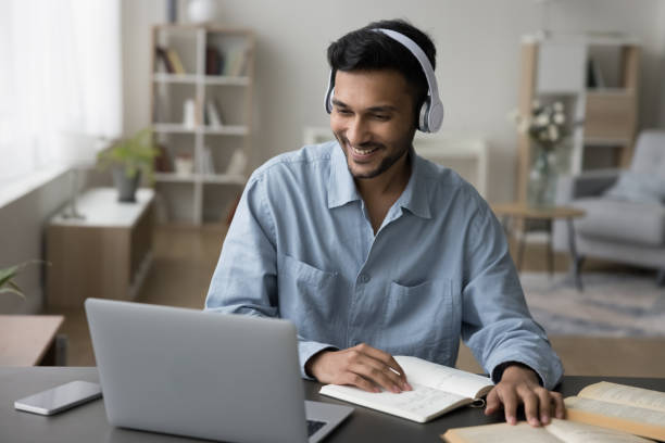istock Cheerful young Indian student guy in headphones watching learning video 1501772354