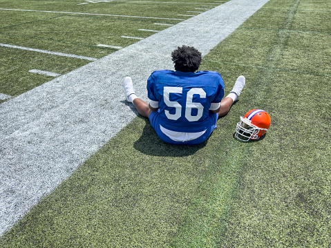 American football player resting  in a practice field on a summer day