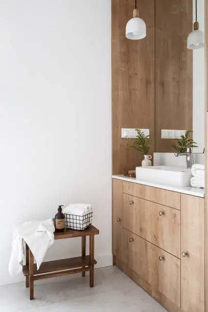 bathroom interior. domestic washroom with ceramic washbasin and faucet, drawers on wooden cabinet under the sink. metal basket with fresh towels and shower gel on table
