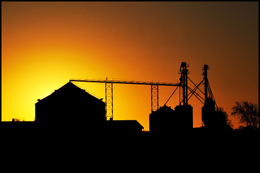 Silhouetted grain bins at sunset.