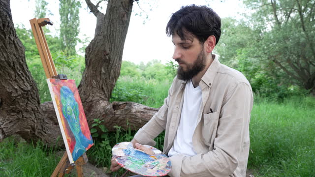 Young male artist painting in nature