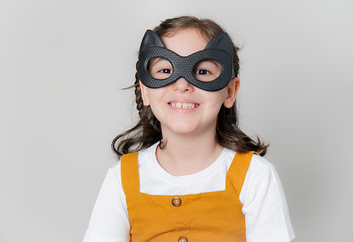 little girl wearing black cat mask isolated on white