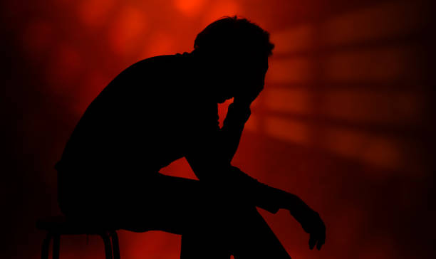 istock man sitting, sad and pensive, loneliness and isolation, red background with lights that transmit anxiety 1501781500