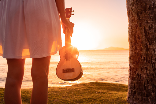 Young woman holding ukulele on the beach.