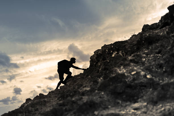Young man climbing up on yellow mountain on ocean background