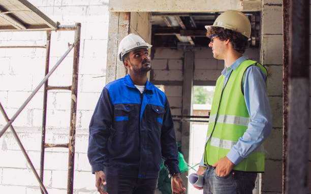 istock Two diversity male engineers team working, inspecting outdoor at construction site, wearing hard hats for safety, talking, discussing, planning for building. Career, Industry Concept. 1501785785