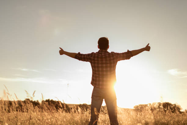 istock Young man feeling grateful, joyful standing outdoors in the sunrise 1501785877
