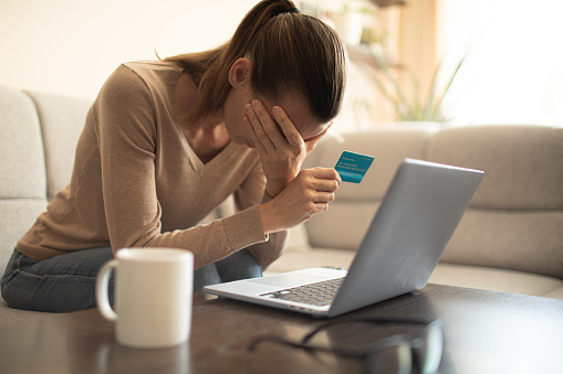 Woman looking stressed and worried with card payments and home finances accounting costs charges taxes and mortgage in paying bills financial problems and credit card debts concept.