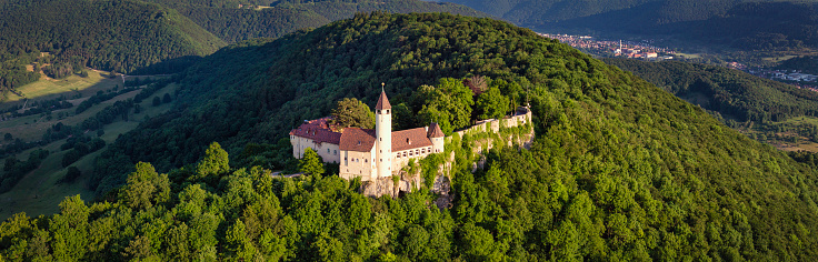 Owen, Germany - June 11, 2023: Swabian Alb in Summer. Drone view over the green summer Swabian Alb Hills. Burg Teck - Teck Castle on top of green hill in sunset light. Stitched XXL Panorama DJI Mavic 3 Pro. Teck Castle, Owen, Swabian Alb, Baden Württemberg, Southern Germany, Germany, Europe.