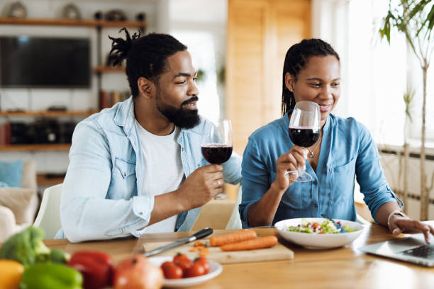 istock Black couple drinking wine while using a laptop in their kitchen 1501791169