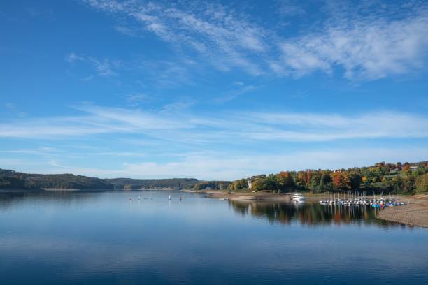 istock Shore of lake surrounded by fall colored trees and a blue sky in the background 1501792368