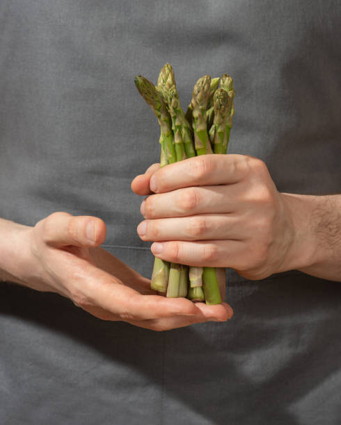 istock A man holds asparagus in his hands in a gray apron, close-up 1501792633