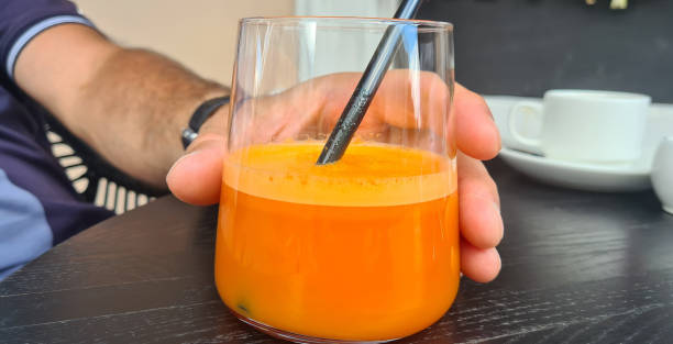 istock Hand and glass cup with orange or carrot juice 1501794094