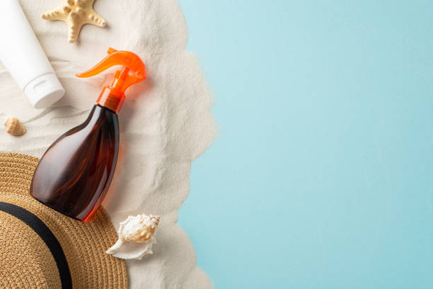istock Sun-Ready Accessories: Get ready for UV Awareness Month with this top view composition featuring unlabeled sunblock oil, SPF cream bottles, sunhat, shells, starfish on light blue and sandy background 1501794177