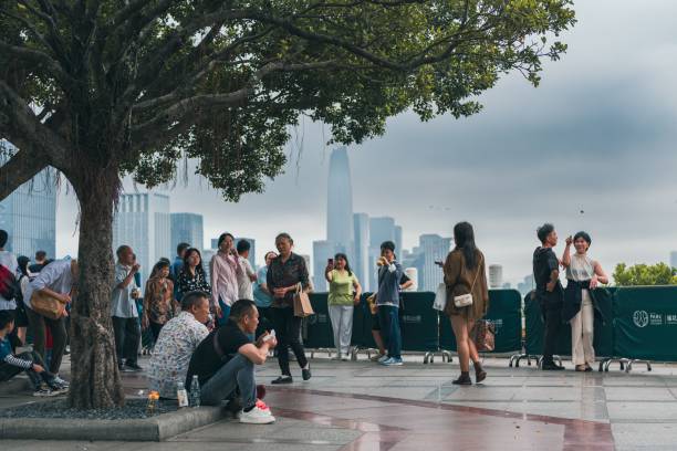 grupo diverso de adultos parados juntos en una acera de la ciudad frente a un árbol en shenzhen - urbanity fotografías e imágenes de stock