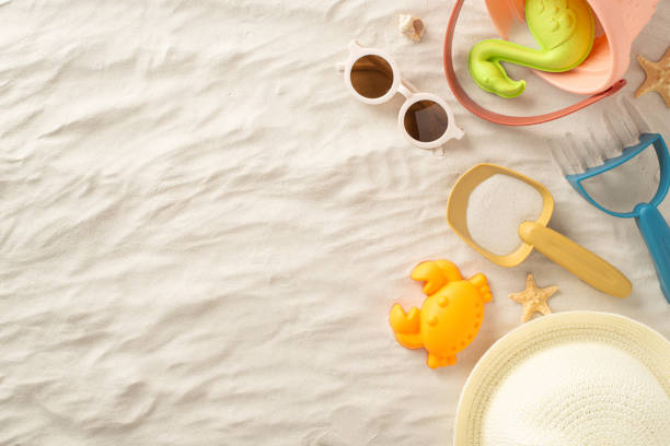 istock Top view photograph featuring a beach setting with panama hat, sand toys for sandcastle, seashells and starfish and sunglasses on sand. Copy space available for advertising a family summer vacation 1501803333