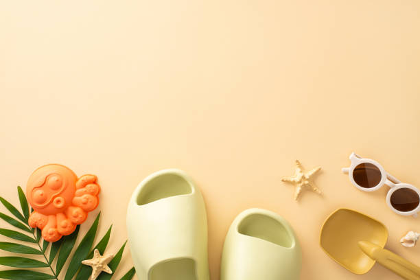 Fun-filled beach escape with young child. Top view shot of sandcastle tools, sunglasses, rubber slippers, starfish, palm leaf on pastel beige backdrop. Ideal for ad family-oriented beach experiences escapada a la playa llena de diversión con un niño pequeño. foto de vista superior de herramientas de castillo de arena, gafas de sol, zapatillas de goma, estrellas de mar, hoja de palma sobre fondo beige pastel. ideal para experiencias de playa orienta