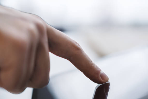 istock Man's finger operating a modern tablet device placed on a desk, within the blurry contours of a well-lit office space 1501809411