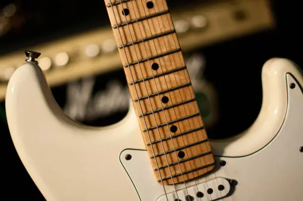 Detail of electric guitar with amp on background