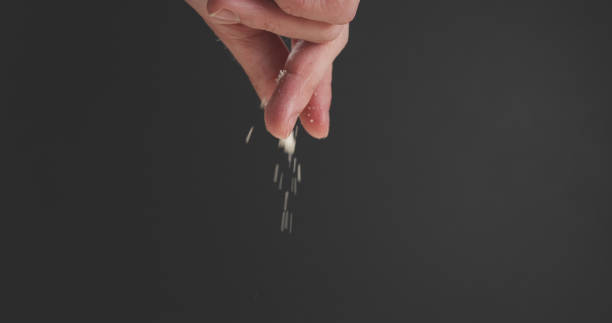 closeup of man hand sprinkle grated aged parmesan over dark background