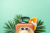 Embark on a journey with a captivating teal setting, featuring a suitcase, beach accessories, sunglasses, sunhat, towel, palm leaves. Great for travel promotions