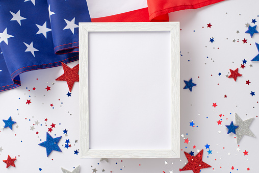 US Independence Day concept. Top view photo of empty wooden frame surrounded by blue, white and red glitter stars and american flag on white isolated background with copy-space