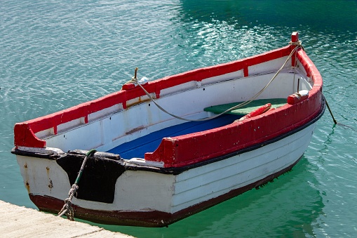 A wooden boat is tied to a dock on the shore of a lake