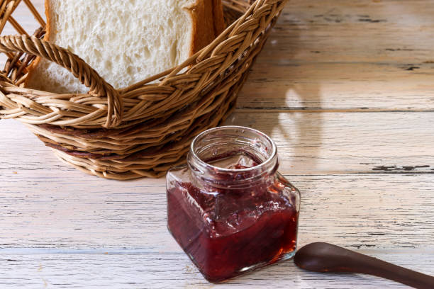 istock Strawberry jam in a glass bottle and breads in a basket on the table. 1501899721