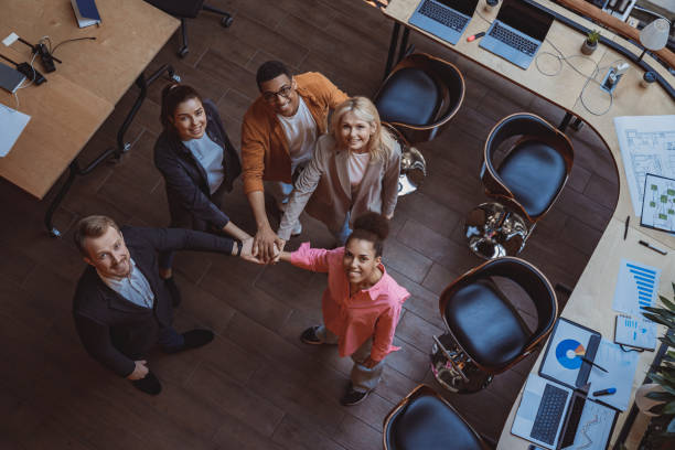 istock Group of coworkers stacking hands together one by one in unity and looking up 1501911715