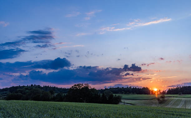 istock Sunset in a cloudy sky over a hilly rural valley with forests and wheat fields 1501921179