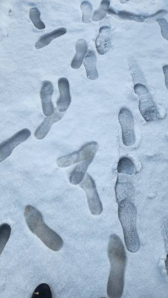 dirt floor covered with layer of snow and traces of people's shoes on the surface in a disorderly manner stock photo