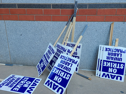 Labor union on strike picketing signs resting on a wall.