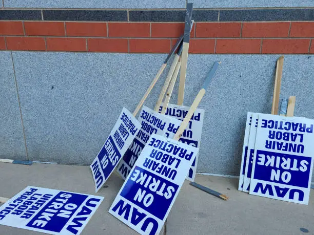 Photo of Labor union on strike picketing signs resting on a wall.