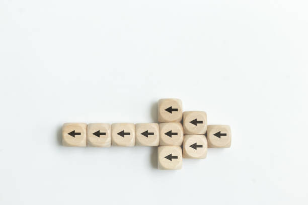 Arrow icon on wooden cubes with little arrow icons pointing opposite direction. Resistance to change in business concept. Arrow icon on wooden cubes with little arrow icons pointing opposite direction. Resistance to change in business concept. bending over backwards stock pictures, royalty-free photos & images