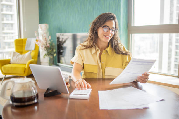 istock Young woman using calculator while going through bills and home finances 1501976841